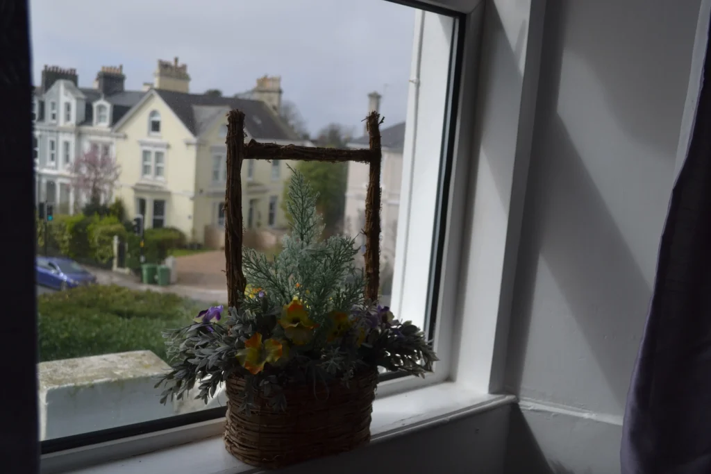 A basket of flowers on a bedroom windowsill at Chatsworth, looking out onto the street