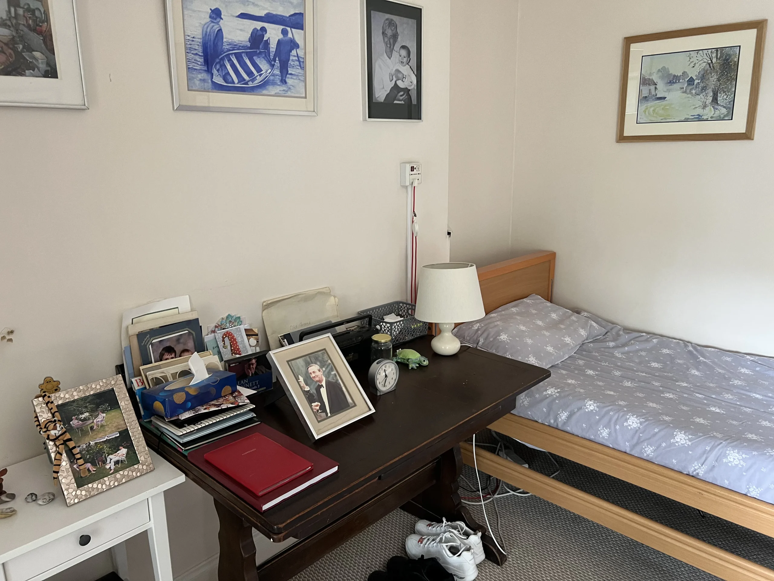 A resident’s room at Chatsworth with a writing desk, framed family photographs and a single bed