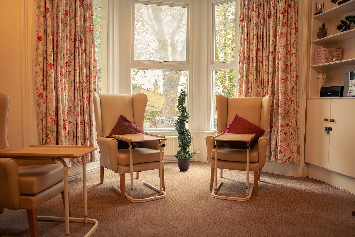 A lounge at The Elms with two armchairs set in front of a large bay window