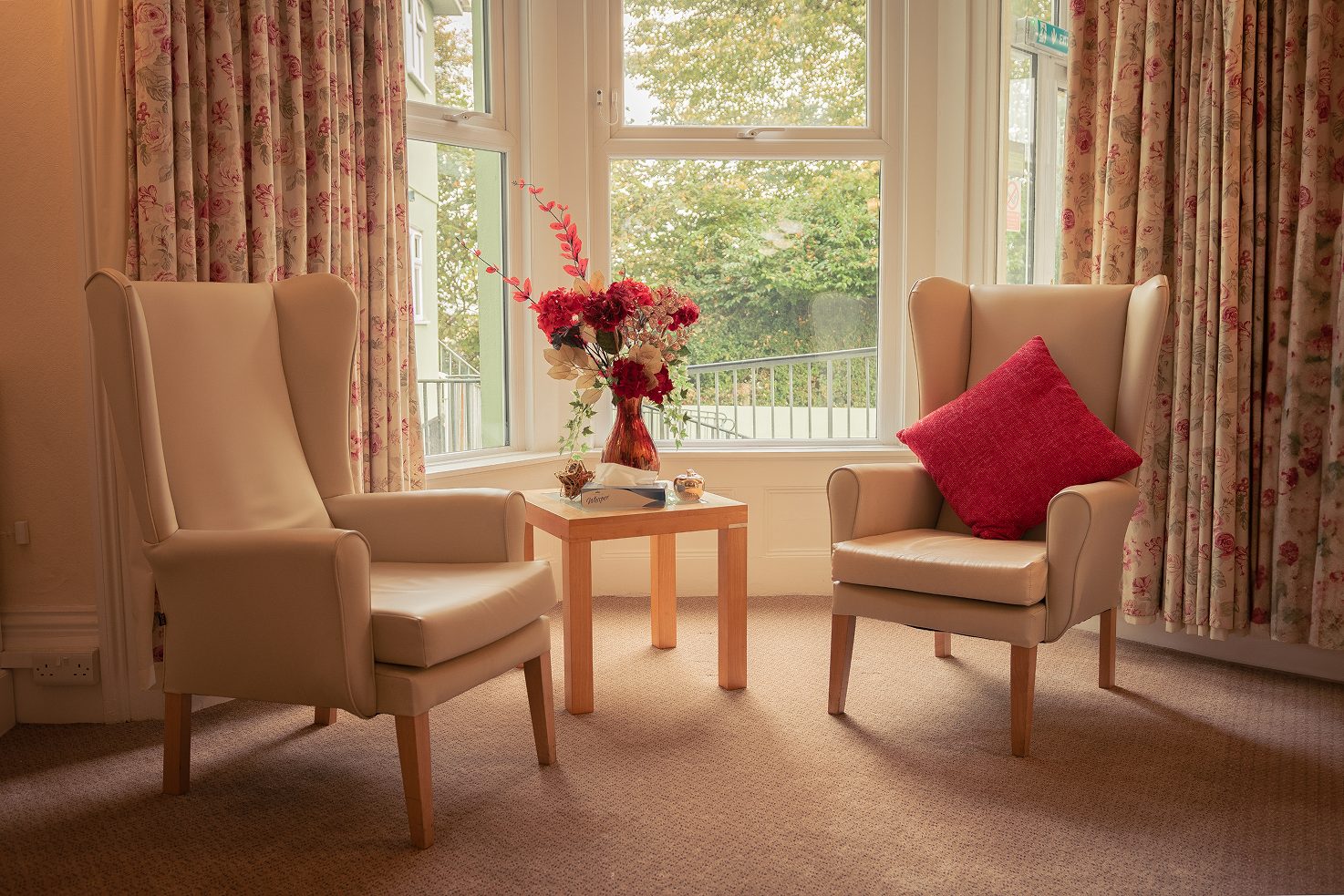 Two armchairs and a side table beside a window overlooking the garden